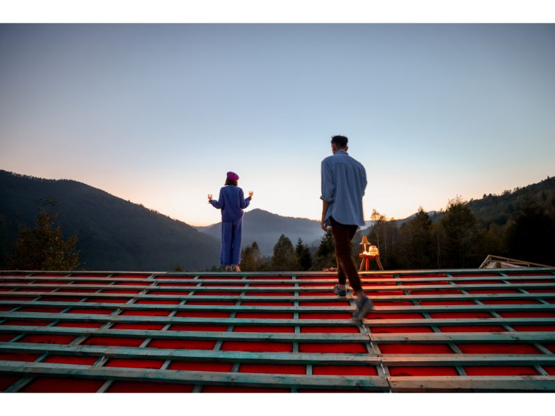 Two people standing on a roof structure at sunset
