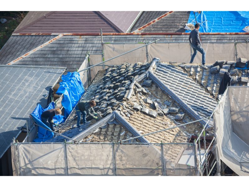 Roofing crew removing damaged tile materials from a roof