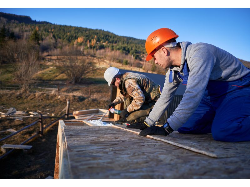 Builders installing insulation on a flat roof deck