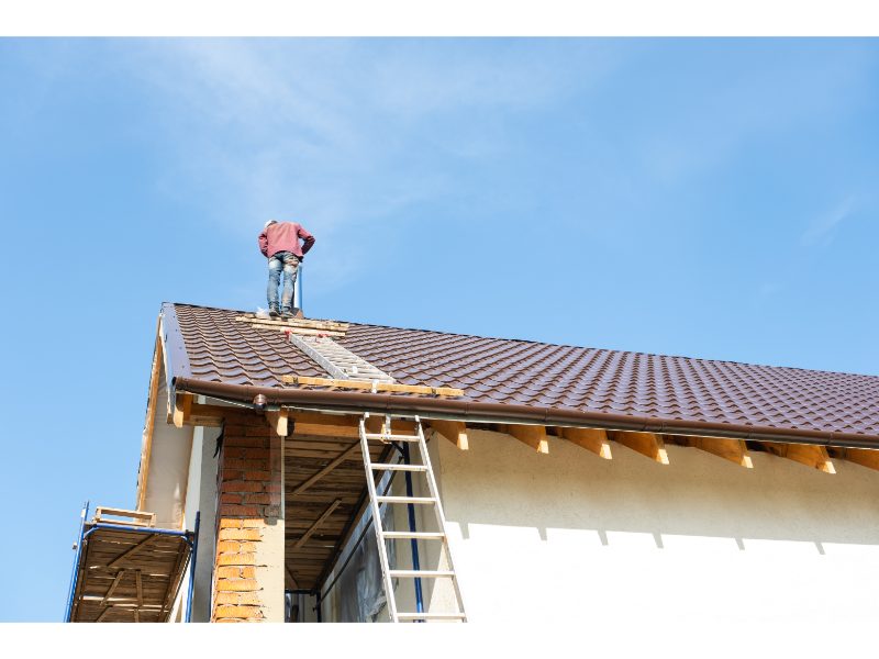 Roofing specialist working near a ventilation pipe on a tiled roof
