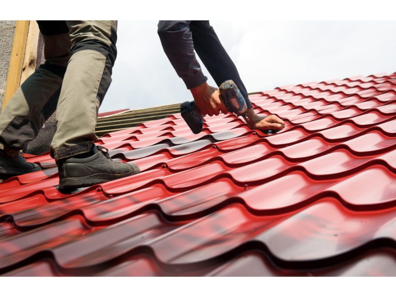 Roofer fastening metal roof panels during a repair